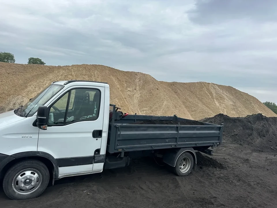 Biały bus wywrotka Iveco Daily na placu budowy przy hałdach piasku — KanTrans